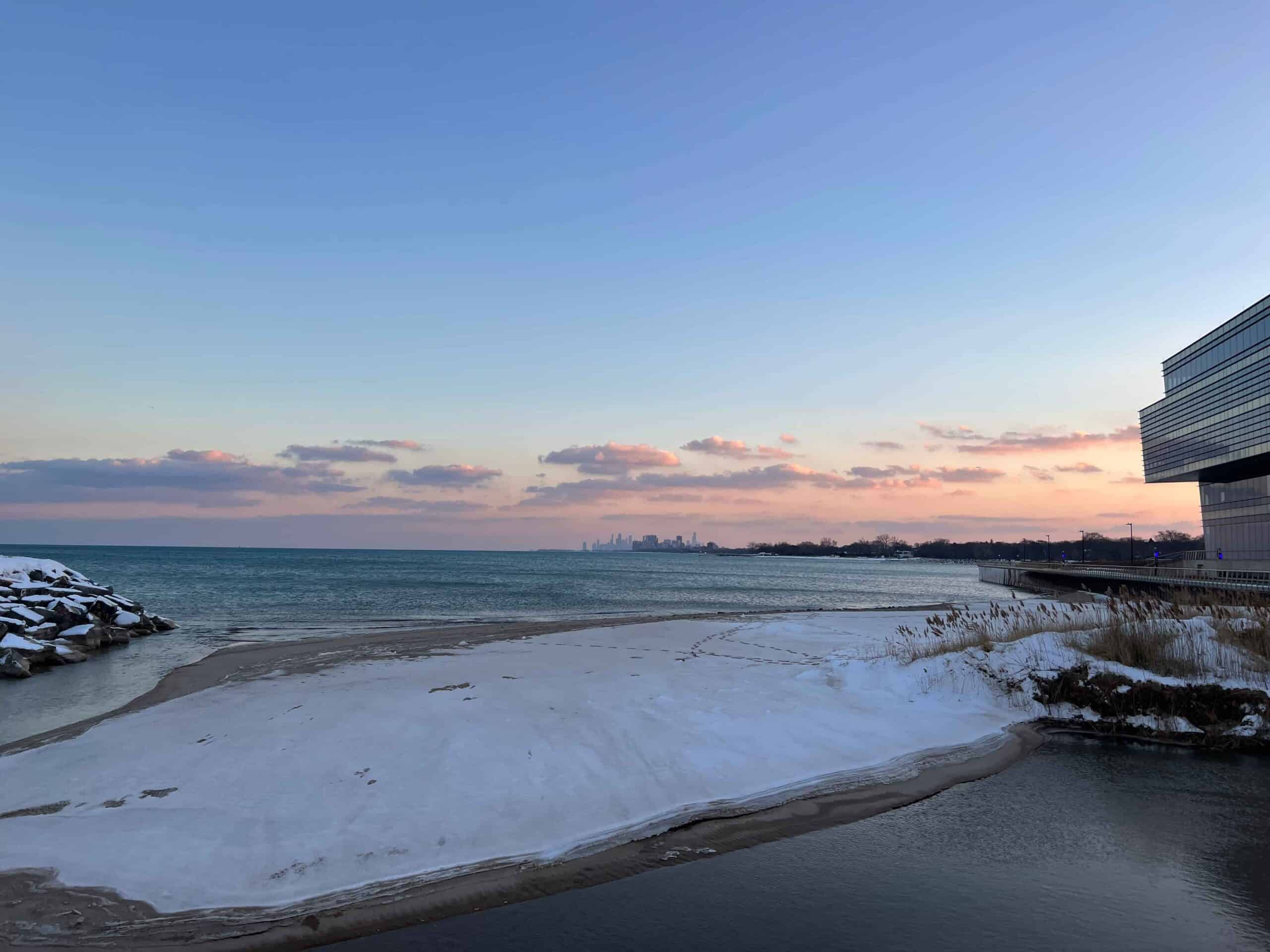 Lake Michigan is covered in snow, with the Chicago skyline in the background