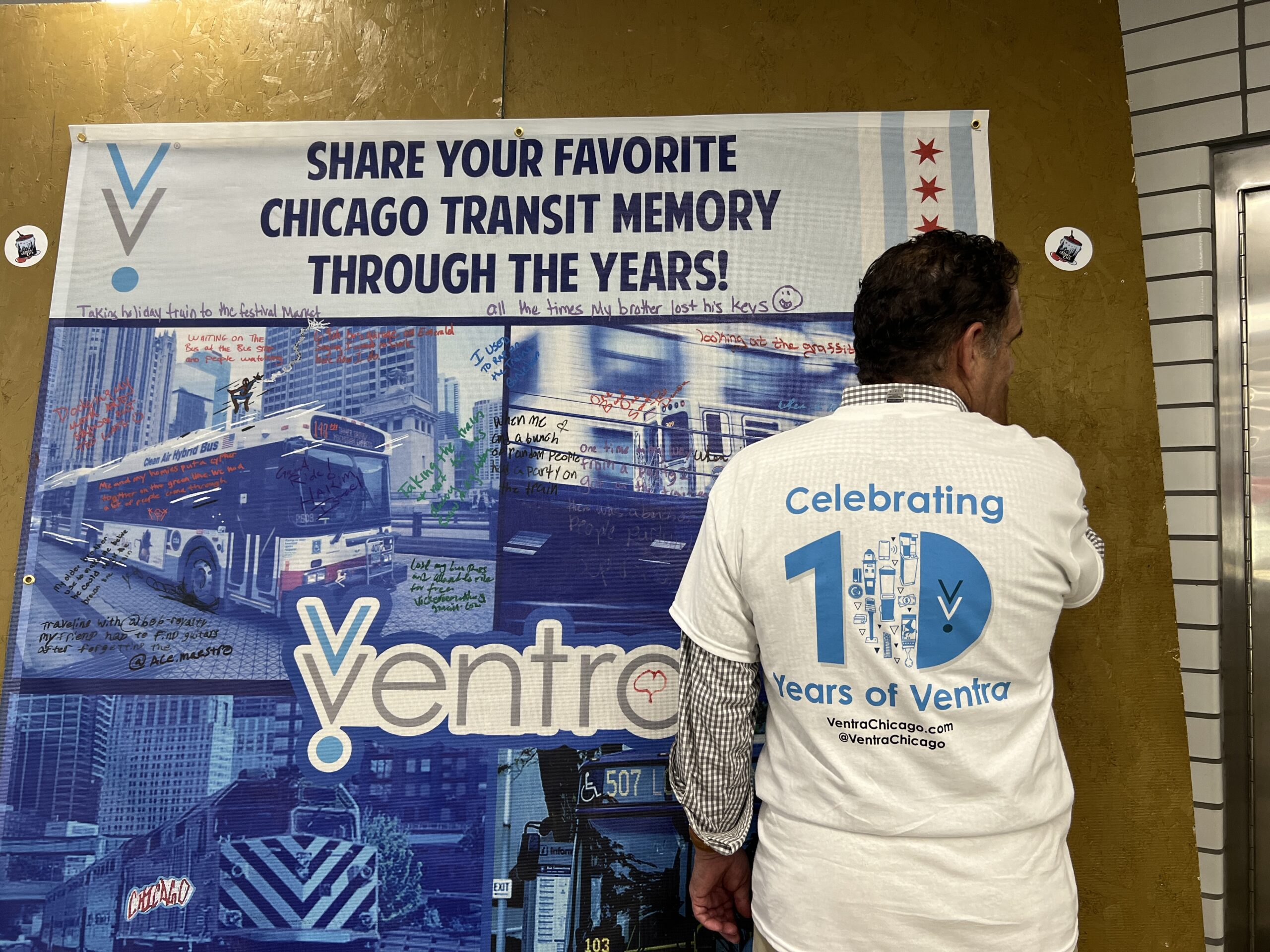 A man writes on a banner that says "Share your favorite Chicago transit memory through the years"