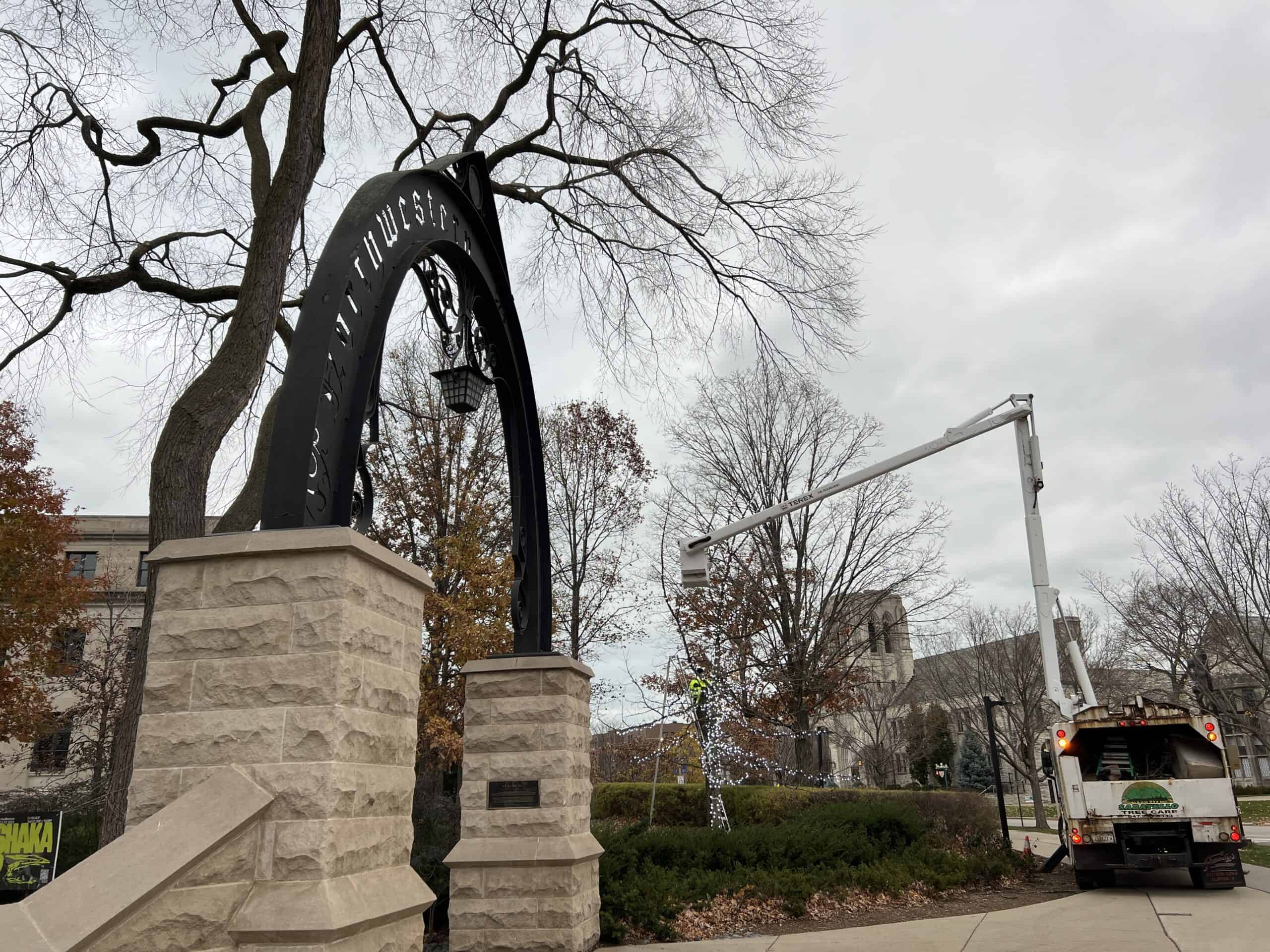 Northwestern's Weber Arch with a bucket truck stringing lights in a nearby tree